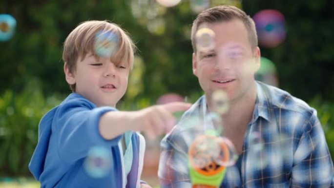 父亲和儿子一起在阳光明媚的公园吹肥皂泡快乐的小男孩玩得开心爸爸和孩子玩得很开心，享受夏天4k