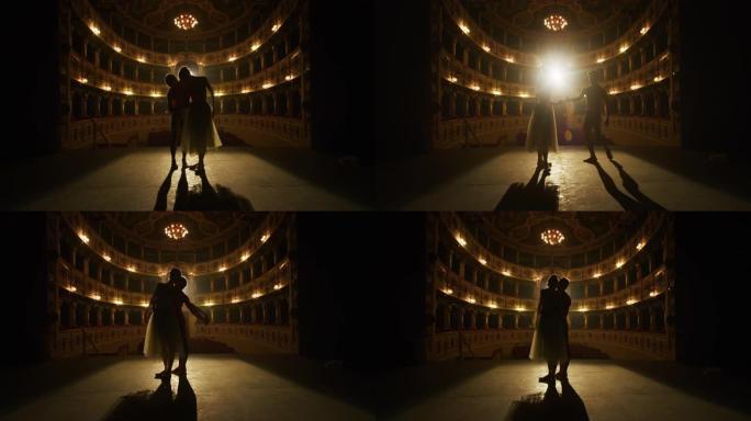 两名年轻的古典芭蕾舞演员在经典剧院的舞台上表演的电影镜头，并带有戏剧性的灯光。男女表演者在演出前一起
