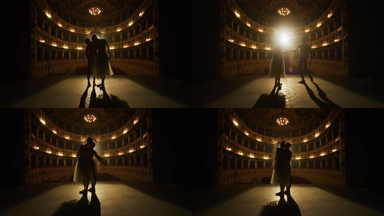 两名年轻的古典芭蕾舞演员在经典剧院的舞台上表演的电影镜头，并带有戏剧性的灯光。男女表演者在演出前一起