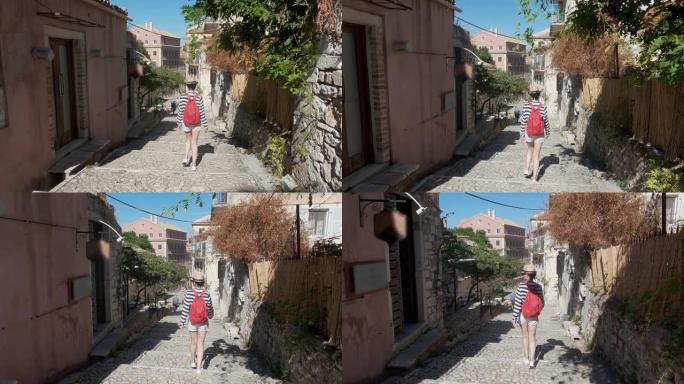 旅游妇女走在楼梯上，探索希腊科孚岛古老的欧洲城市狭窄的街道。女士观光当地建筑。夏天，她在镇上闲逛，慢