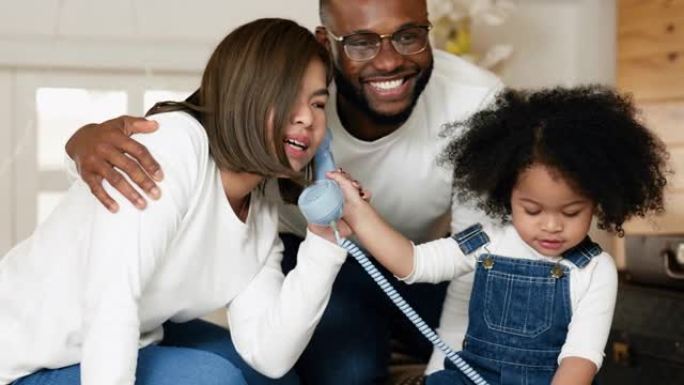 多种族的新手父母正在示范和教导使用和接听电话给他们的女儿。
