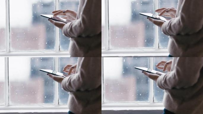 关闭女人的手使用数字平板电脑浏览在线消息阅读社交媒体享受移动触摸屏设备站在窗前放松在寒冷的雨天在家
