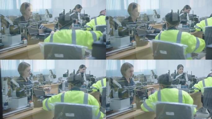 员工正在通过遥控器操作焊接机器人，他们穿着安全服，安全帽和安全镜，在焊接车间工作，高级员工在工作区域