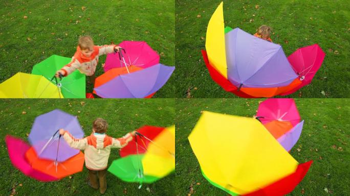 男孩用六把雨伞在草地上旋转
