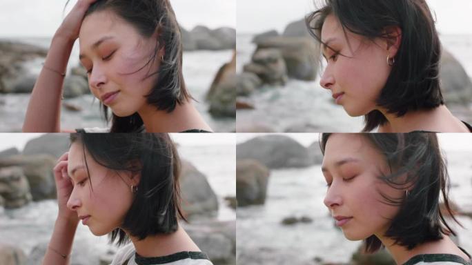 美丽的亚洲女人的肖像，微笑着享受多云的海边，探索度假的生活方式，风吹着头发在海滩上