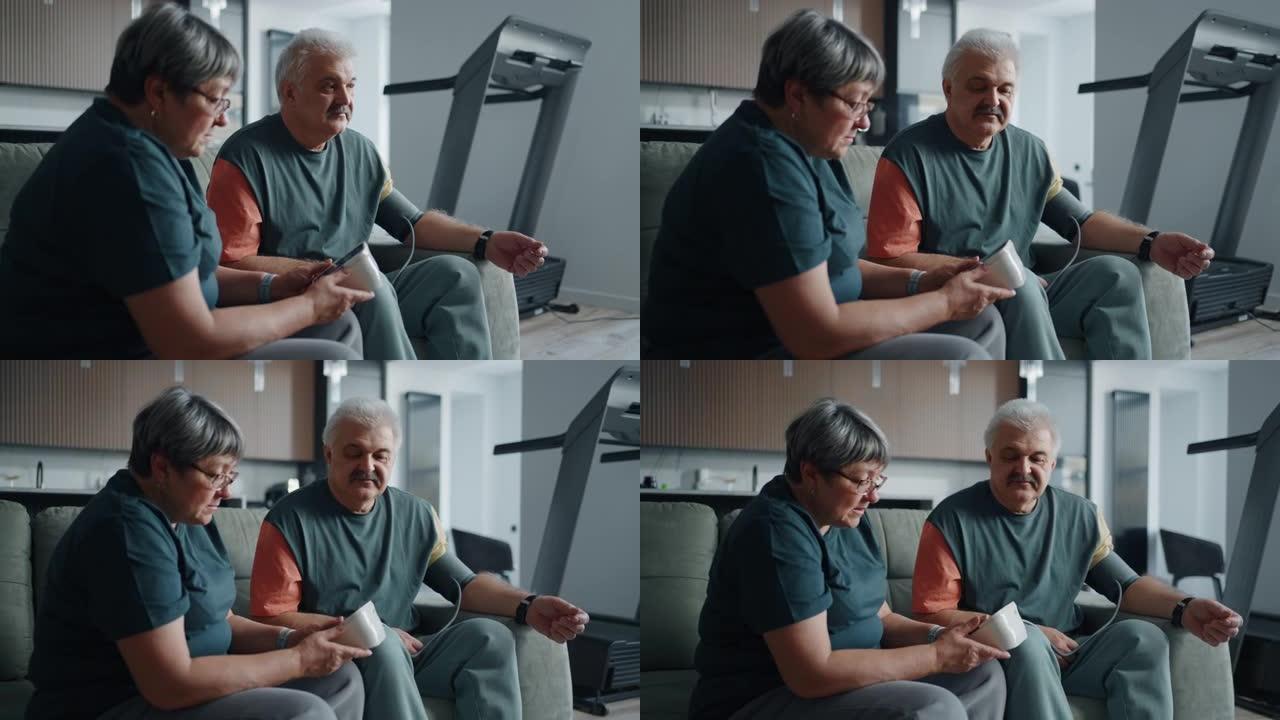 老人和他的妻子坐在家里的沙发上，用血压计测量血压