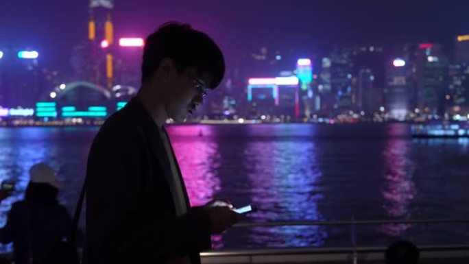 商人在香港夜城散步时使用智能手机