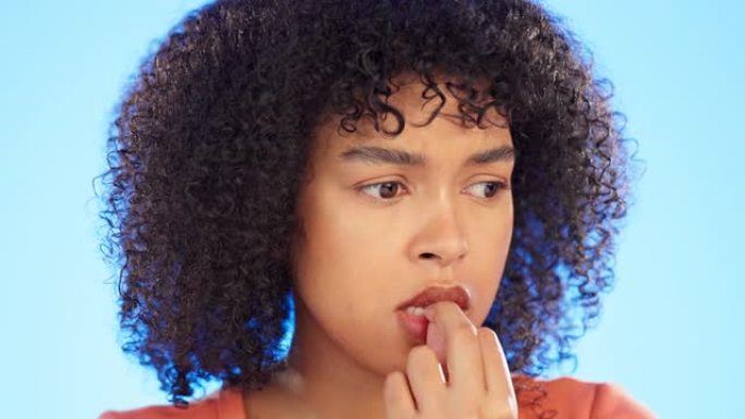 黑人妇女咬指甲，焦虑和紧张的脸，精神卫生和恐惧孤立在蓝色背景上。女性害怕，在工作室里思考危机或压力和