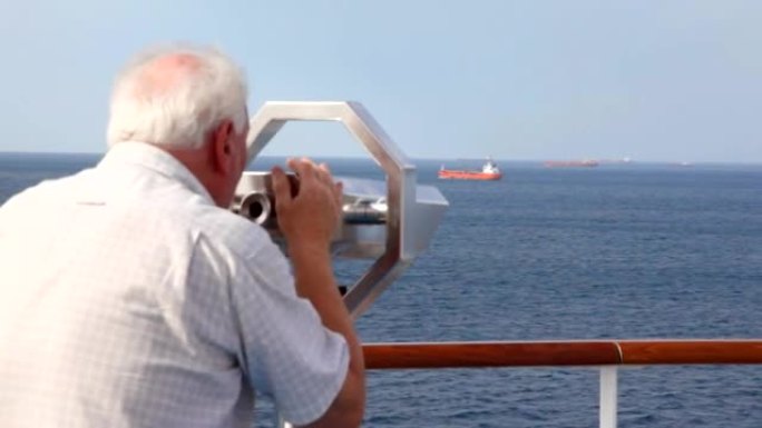 老年男子透过甲板上固定的双筒望远镜