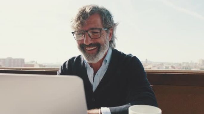快乐的中年男子用笔记本电脑远程交流。在家办公