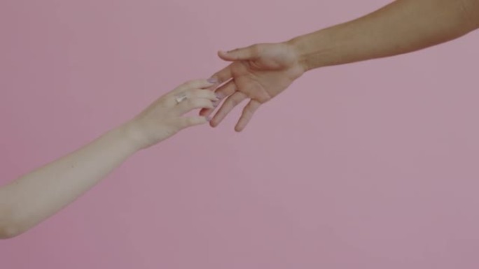 双手的特写男性和女性伸手然后触摸粉红色的背景