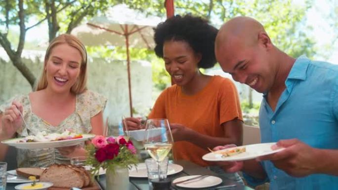 一群朋友在参观葡萄园餐厅时享受户外美食和葡萄酒