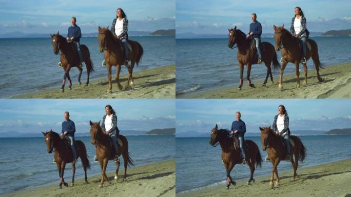 幸福的女人和男人的肖像在海边骑马，在背景中与明亮的蓝天交谈。年轻的马术夫妇喜欢他们的爱好，好天气和自