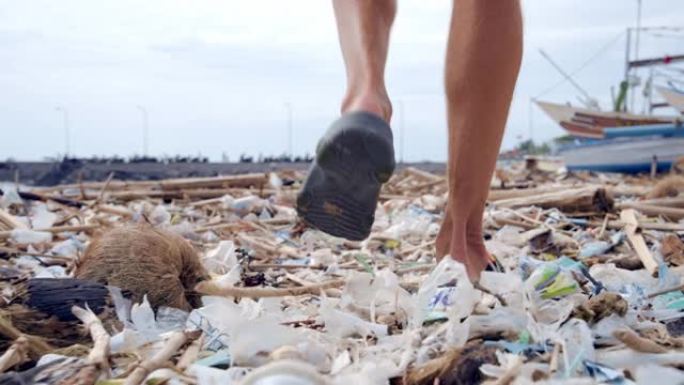 垃圾对海滩生态和环境自然的污染。由男性在垃圾和废物上移动的世界生态控制。水岸地球中危险的瓶子，袋子和
