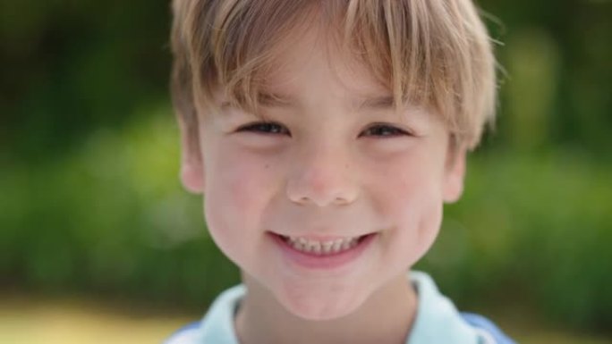 肖像快乐的小男孩带着顽皮的兴奋微笑着看着相机在阳光明媚的公园享受童年的乐趣4k镜头