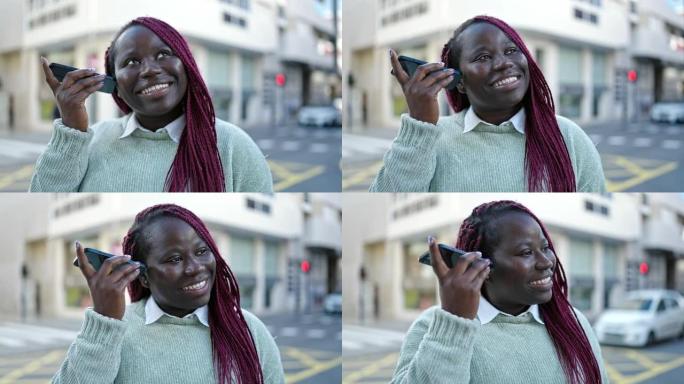 编织头发的非洲妇女在街上用智能手机收听语音信息