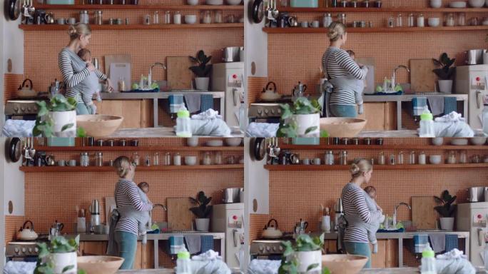 年轻的母亲抱着睡着的婴儿在家打扫厨房工作家务妈妈享受母亲的责任照顾孩子