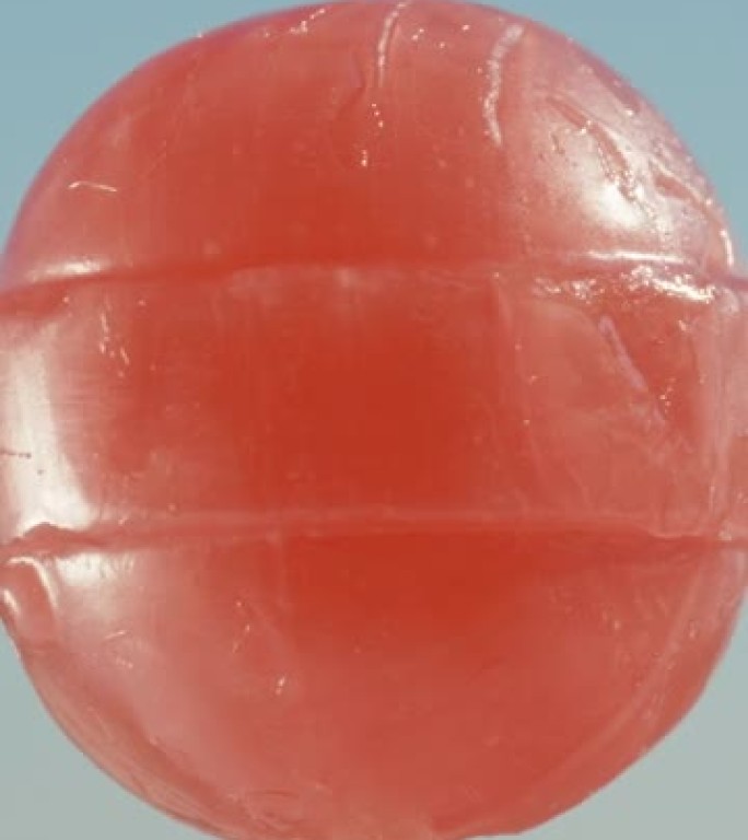 一根红色的圆形棒棒糖，对着天空旋转。特写。垂直视频社交媒体