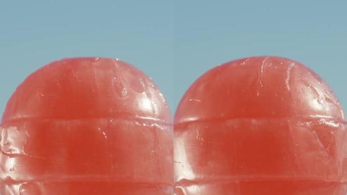 一根红色的圆形棒棒糖，对着天空旋转。特写。垂直视频社交媒体