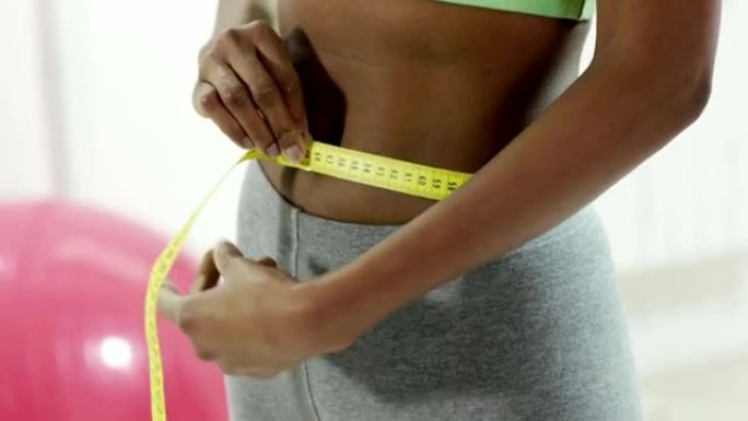 年轻的黑人妇女在健身房测量腰部