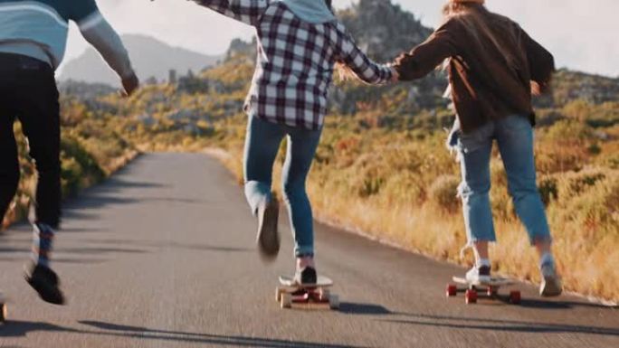 年轻的多民族朋友一起牵手骑滑板在乡村道路上下坡巡航，享受轻松的暑假
