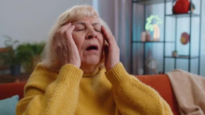 不高兴的祖母妇女擦太阳穴以治愈偏头痛压力引起的头痛问题
