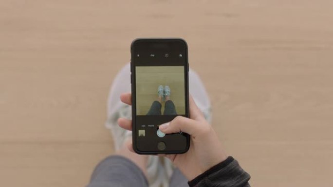顶视图女性手使用智能手机拍摄新鞋的照片在社交媒体上分享摄影享受时尚时尚