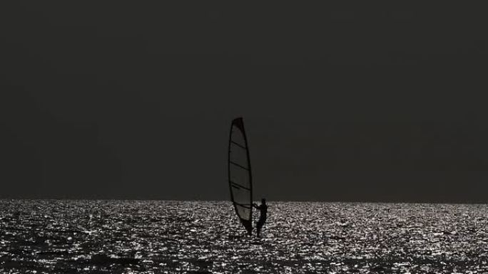 在傍晚的灯光下滑浪风帆。