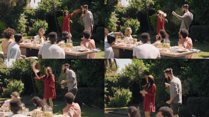 快乐的夫妇在花园派对上与朋友跳舞庆祝，在美丽的夏日享受野餐午餐，激动人心的周末聚会