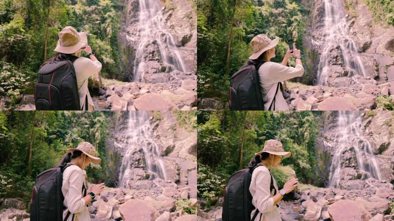 亚洲女孩徒步旅行用手机拍照瀑布。