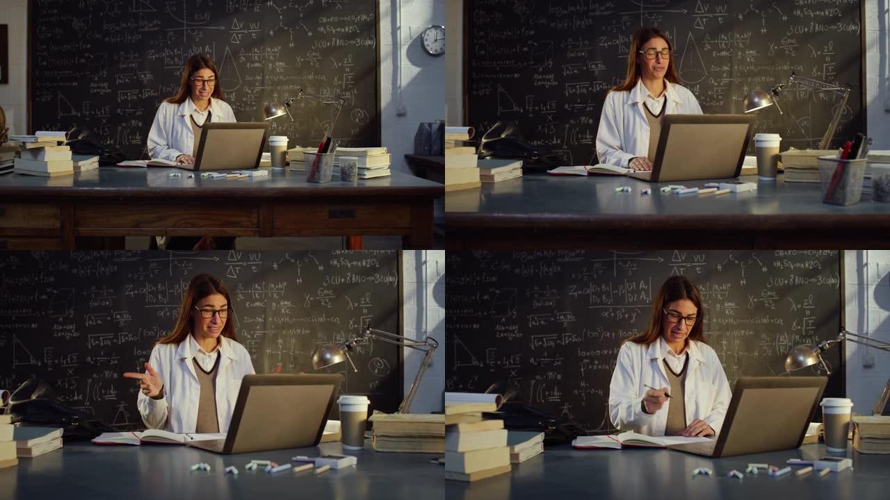 教室里年轻女教师的肖像使用笔记本电脑在带有公式的黑板前进行远程授课。科学教授在线教学，与学生进行视频