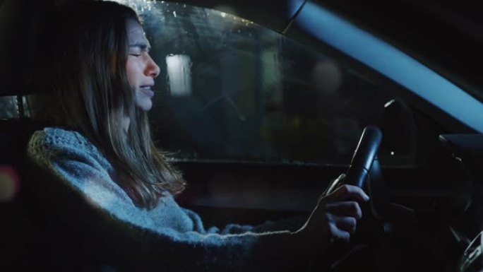一个愤怒的年轻女子在雨夜坐在车里尖叫的肖像。女司机在与伴侣发生冲突后，对坏消息感到沮丧，情绪激动，撞
