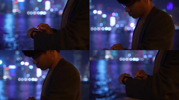 香港城市之夜使用智能手表的商人
