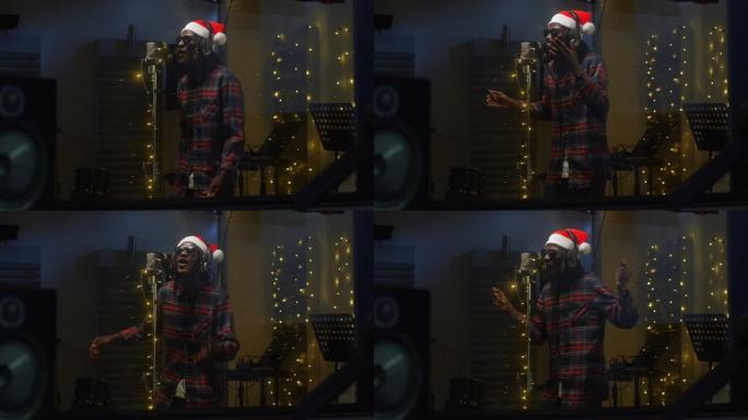 一位职业男性黑人歌手的肖像在录音室为他的圣诞节专辑录制了一首歌。戴着圣诞老人帽子的非洲年轻艺术家喜欢