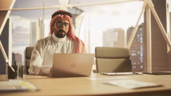 一位穆斯林商人在金融科技初创公司的笔记本电脑上工作的肖像。阿拉伯金融分析师在新兴的中东股票市场进行研