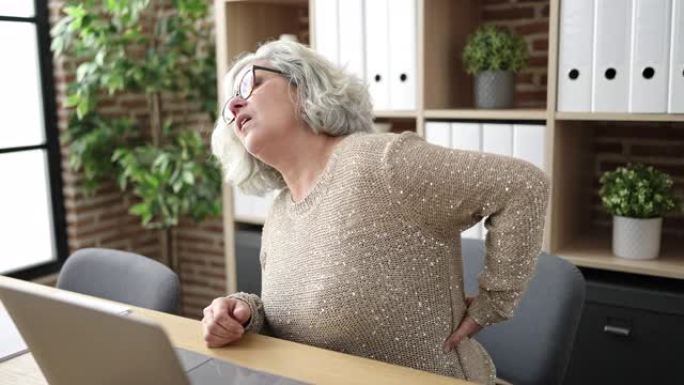 中年妇女，头发花白的商业工作者在办公室因背痛而受苦