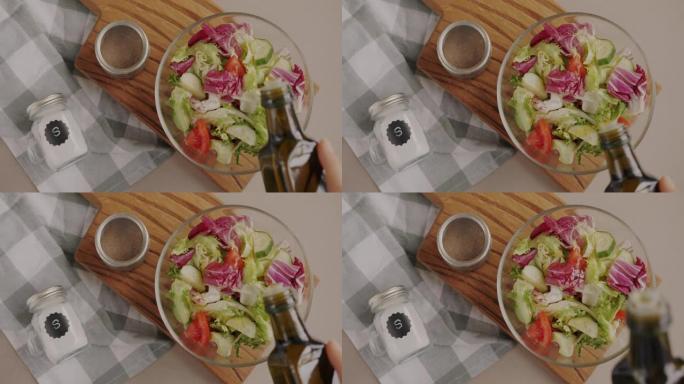 手工在沙拉中倒入橄榄油制作健康蔬菜的俯视图