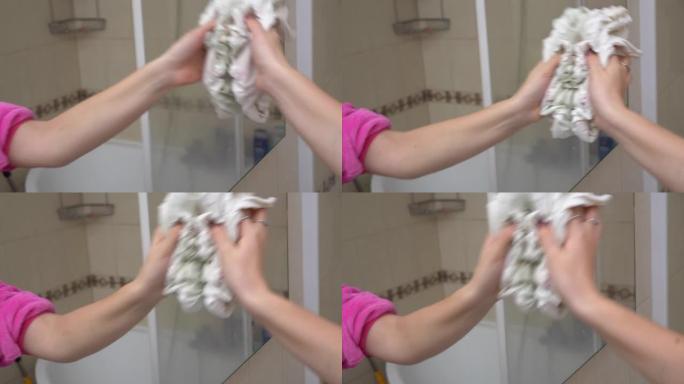 女人在浴室里用抹布擦拭镜子。