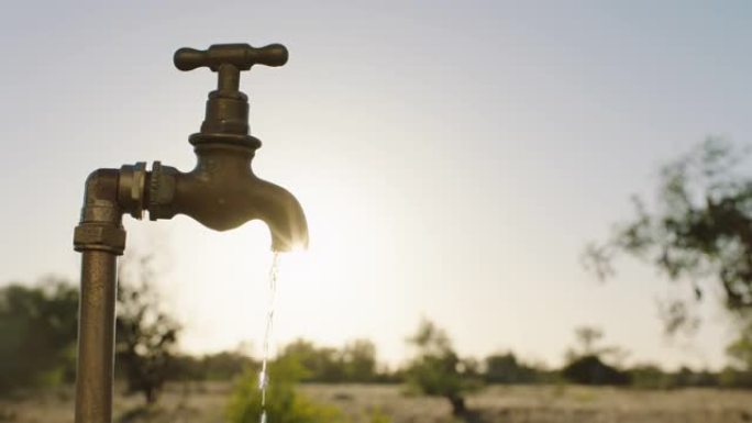 日落时分，农村农场的自来水从水龙头流出，室外的淡水浪费了农田干旱造成的水资源短缺