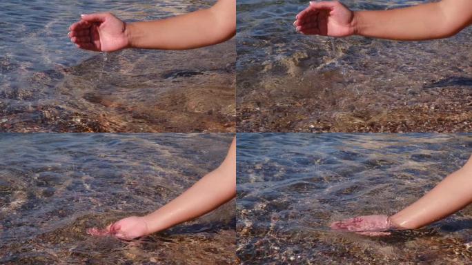 女人的手倾泻着海水，享受着新鲜。沿海与自然统一的概念。