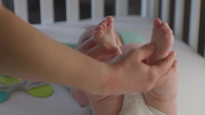 母亲触摸或按摩可爱的新生儿腿