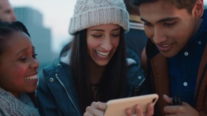 年轻女子使用智能手机向一群不同的朋友展示社交媒体娱乐在日落时享受屋顶派对