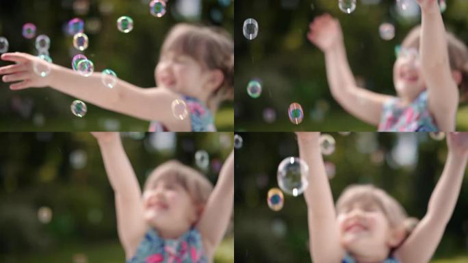 快乐的小女孩嬉戏地捕捉肥皂泡漂浮着可爱的孩子在阳光公园无忧无虑的童年游戏4k