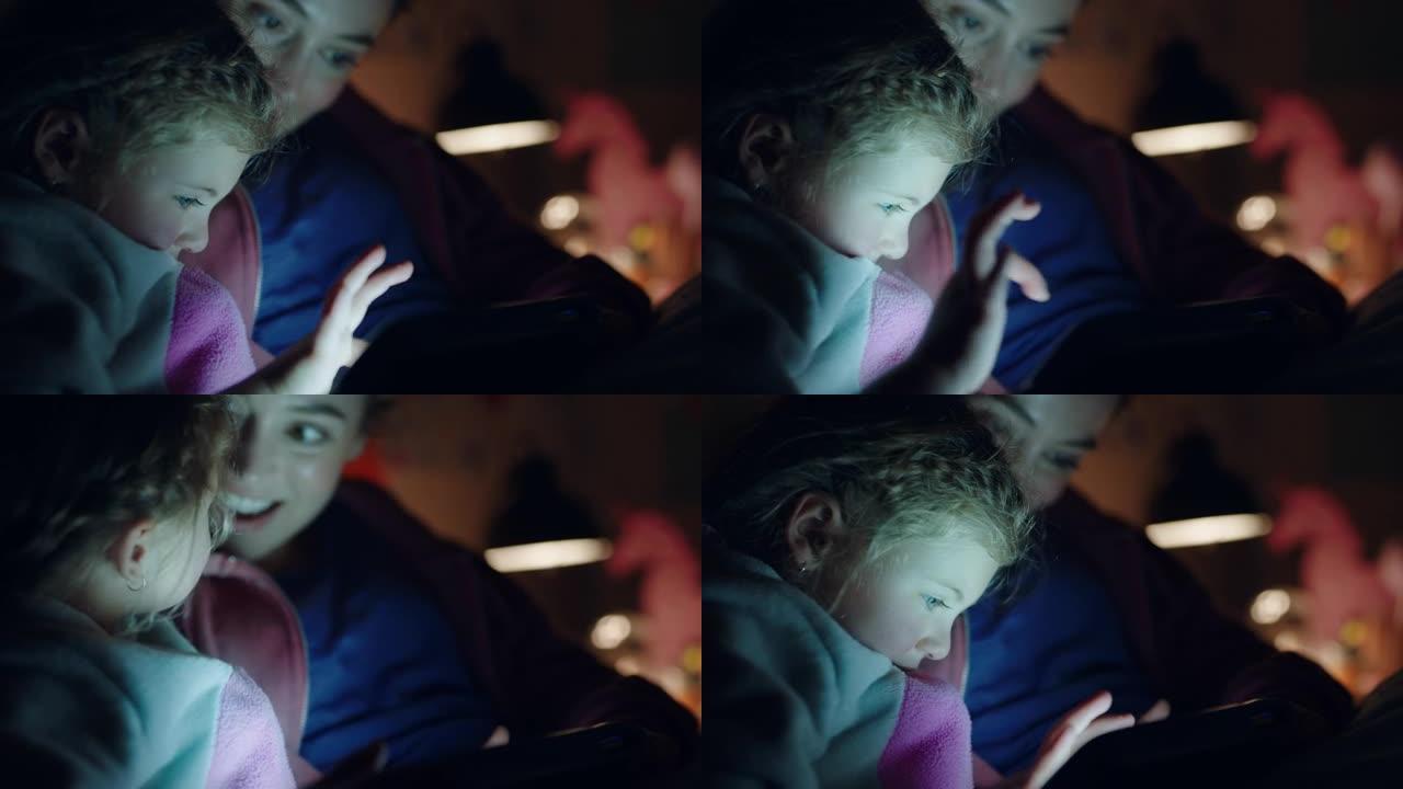 母亲和孩子使用平板电脑妈妈教小女孩在触摸屏技术上玩游戏睡前玩得开心
