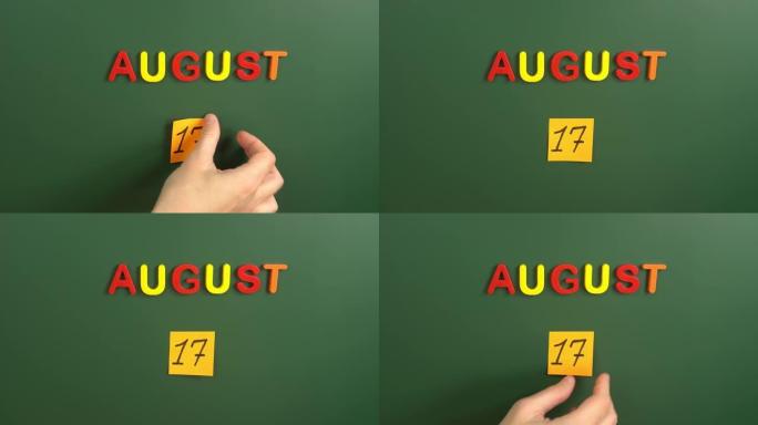 8月17日日历日用手在学校董事会上贴一张贴纸。17 8月日期。8月的第十七天。第17个日期编号。17