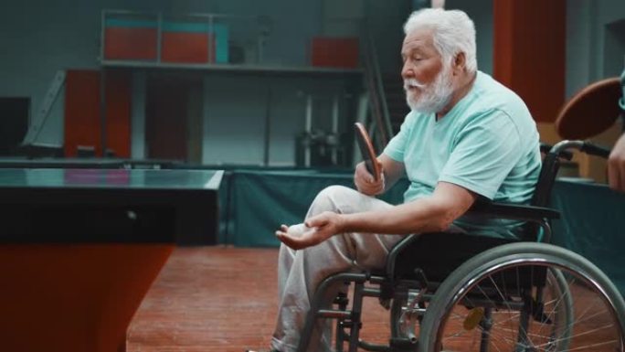 乒乓球发球概念。专注的残疾老人打乒乓球。