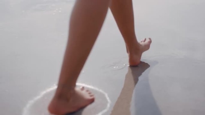 近距离女子脚赤脚走在海滩上享受温柔湿润的海沙暑假女游客
