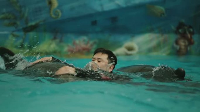 亚洲男子与海豚一起游泳