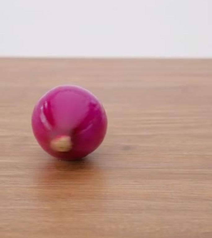 垂直视频，木桌背景上红洋葱旋转的慢动作，特写