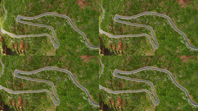 带有行驶中的汽车的蛇形多风道路的空中俯视图。急转弯上坡的道路。车辆沿着山路移动。